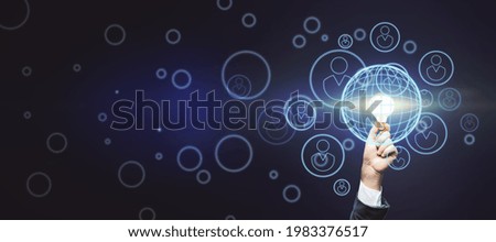 Collective raise money for new idea concept with bright light bulb in businessman hand on abstract dark wallpaper with digital human figures signs. Mockup Royalty-Free Stock Photo #1983376517