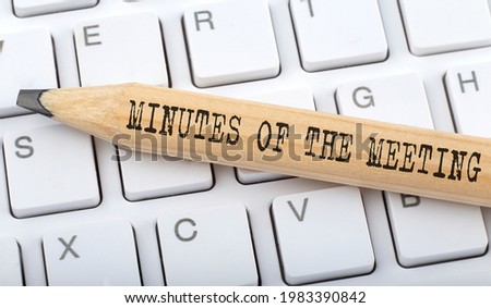 Text MINUTES OF THE MEETING on wooden pencil on white keyboard. Business Royalty-Free Stock Photo #1983390842