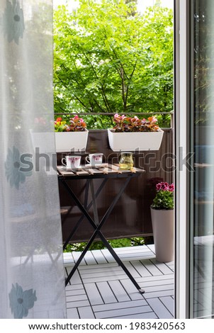 bright small apartment terrace in summer with flowers and coffee table