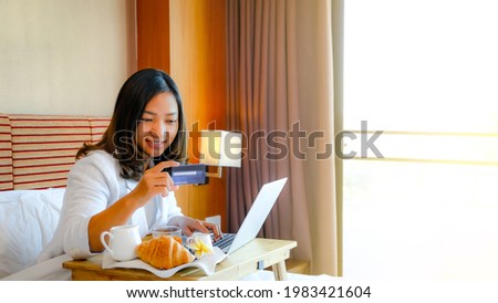 Picture of tourists used laptop and eating breakfast on the bed in the luxury hotel room.
