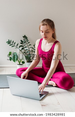 Girl practicing yoga at home. Woman is watching video on the internet and repeating the tasks. Indoor and outdoor workout. Sport and healthy active lifestyle concept.