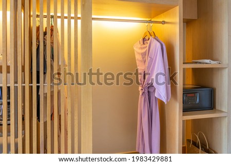 Closeup of fresh bathrobe hanging in wooden wardrobe at luxury hotel. Relax and travel concept
