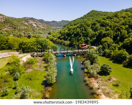 Aerial view of old bridge with a boat passing under it, in Montenegro, Rijeka Crnojevica