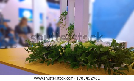 Floristic decor of recreation and networking zone for meeting in expo centre. Green plants and flowers. Business Office interior design. Trade show. Reception Blurred background. Selective focus. Royalty-Free Stock Photo #1983452981