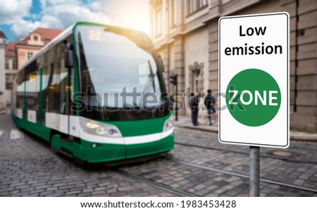Road sign "Low emission ZONE" on a background of green tramway. Clean mobility concept	 Royalty-Free Stock Photo #1983453428