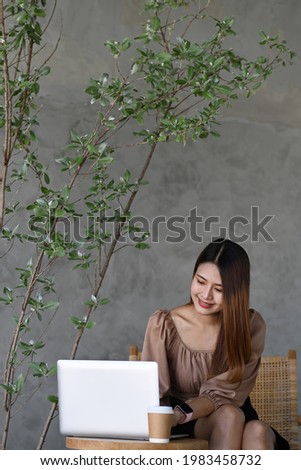 Portrait of cheerful young female using laptop computer at cafe.