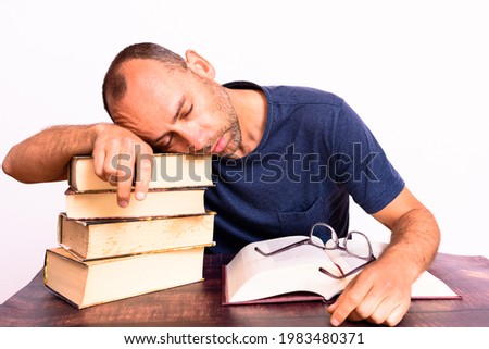 Tired and sleepy mature man on his books, studies to improve his economy.