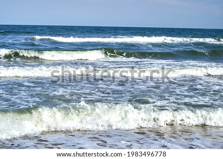 Blue waves with white foam run ashore