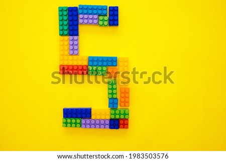 The number five from the children's multi-colored constructor on a yellow background. Empty space for the text.Holiday date.