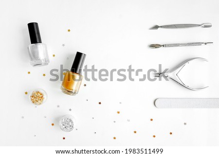 Tools of a manicure set on a white background as frame. Copy space. Golden and silver nail polish and rub.