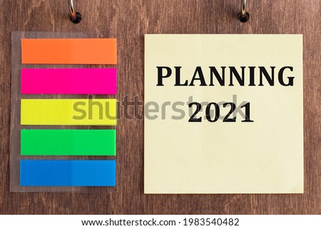 a yellow card with the inscription of Planning 2021 on a wooden background.