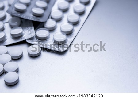 White medical pills are spread on the gray table.