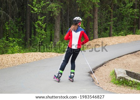 A girl on a roller ski ride in the park.Cross country skilling.