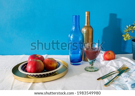 Photo of apples on a plate on a table covered with a tablecloth with a blue wall in the background