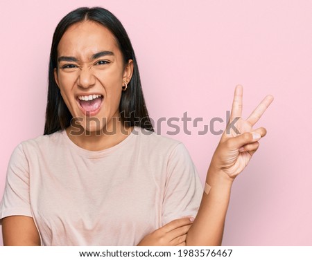 Young asian woman wearing casual clothes smiling with happy face winking at the camera doing victory sign. number two. 