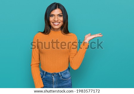 Young latin transsexual transgender woman wearing casual clothes smiling cheerful presenting and pointing with palm of hand looking at the camera. 
