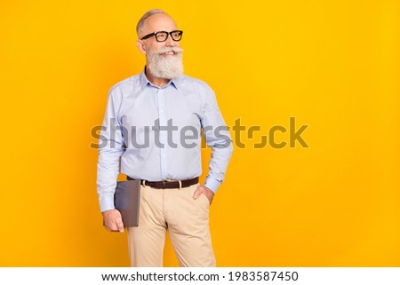Photo of dreamy happy old man look empty space hold hand pocket laptop isolated on yellow color background