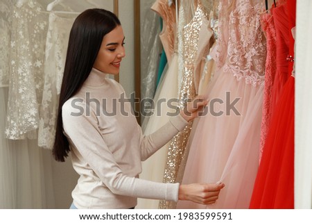 Woman choosing dress in rental clothing salon Royalty-Free Stock Photo #1983599591