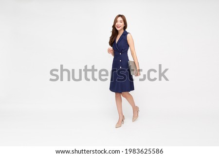 Portrait of a smiling Asian businesswoman holding laptop computer while walking isolated on white background, Full body length composition concept