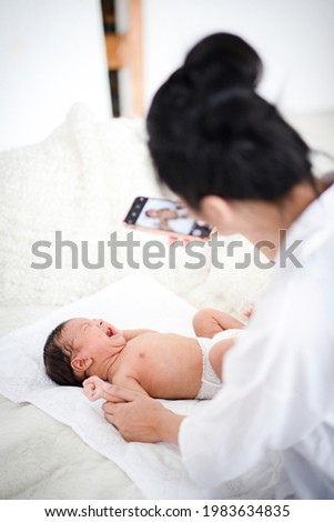 a high angle shot of infant on bed with a smartphone at home. a memorable family portrait, mom taking a photo of newborn, mother and baby 