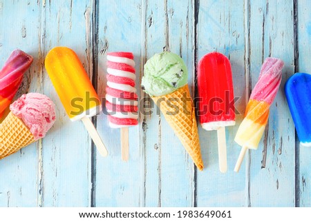 Selection of colorful summer popsicles and ice cream treats. Overhead view scattered on a rustic blue background. Royalty-Free Stock Photo #1983649061