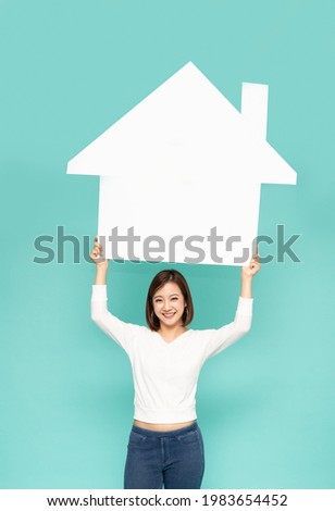 Portrait of smiling Asian woman showing and presenting white home isolated on green background, Real estate residential and rent home concept