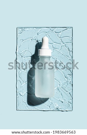 Glass bottle with pipette of cosmetic liquid transparent gel on blue background. Top view, flat lay. Royalty-Free Stock Photo #1983669563