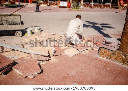 Builder tamping down a new paving brick with a mallet with motion blure effect. Royalty-Free Stock Photo #1983708893