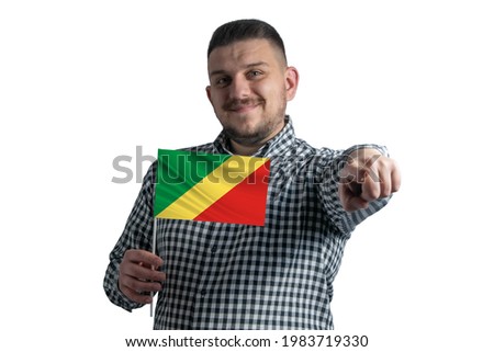 White guy holding a flag of Republic of the Congo and points forward in front of him isolated on a white background.