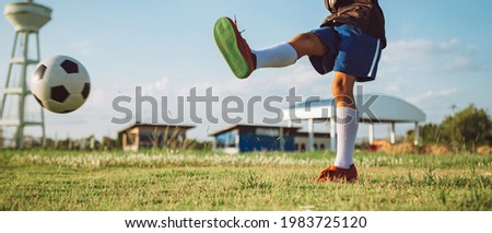 An action sport picture of kids playing soccer football for exercise at the green grass field.