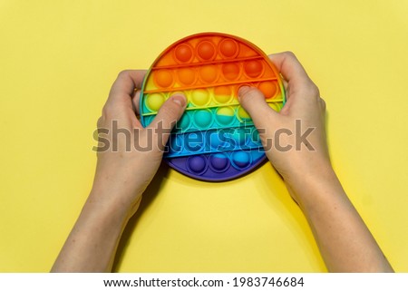 Child play with Pop it sensory toy. Pressing on colorful rainbow squishy silicone bubbles. Trendy fidgeting game. Stress and anxiety relief. Royalty-Free Stock Photo #1983746684