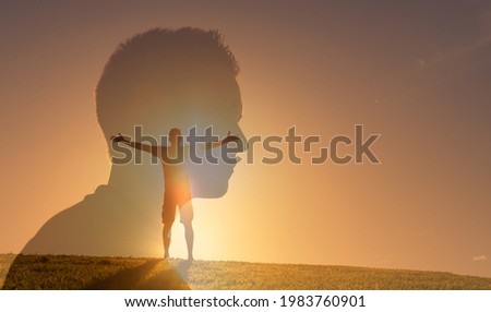 Inner happiness, feeling inspired, and positive thinking concept. Young man silhouette outdoors with arms up to the sunlight sky feeling enlightened and energized. 
 Royalty-Free Stock Photo #1983760901