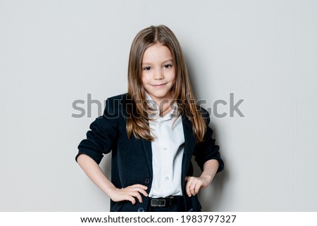 A beautiful girl posing on a light background. A girl in a classic suit, office attire smiles.