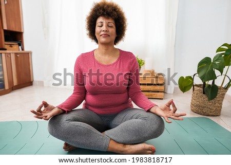 African senior woman doing yoga session at home - Focus on face Royalty-Free Stock Photo #1983818717