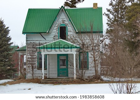 An old abandoned Ontario Cottage style house with a green metal roof. Royalty-Free Stock Photo #1983858608