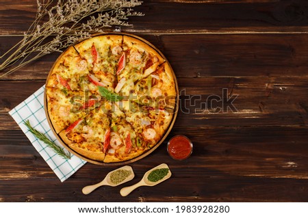 Banner of homemade seafood pizza with shrimp, crab sticks, bell peppers topping on wooden tray, table, decorated by tomato sauce, ketchup, oregano ingredients with napkin in kitchen and copy space