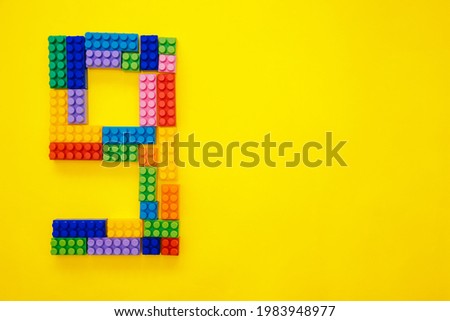 The number nine from the children's multi-colored constructor on a yellow background. Empty space for the text.Holiday date.