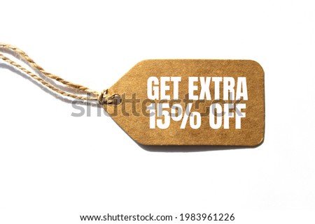 GET EXTRA 15 OFF percent text on a brown tag on a white paper background