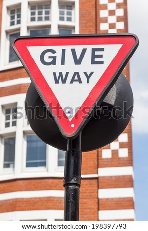 give way sign with and old building in the background in London