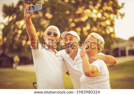 Senior golfers using phone and taking self portrait. Happy picture for album.