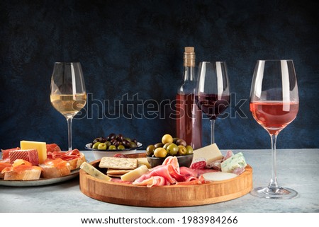 Wine and charcuterie and cheese board with a place for text. Prosciutto di parma ham, blue cheese, olives and salmon sandwiches, Italian antipasti or Spanish tapas, a side view with copy space Royalty-Free Stock Photo #1983984266