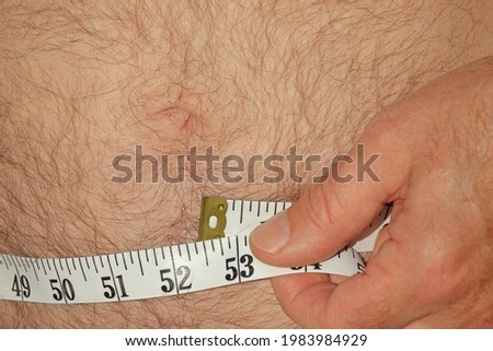 Fat man measuring his hairy belly for size
