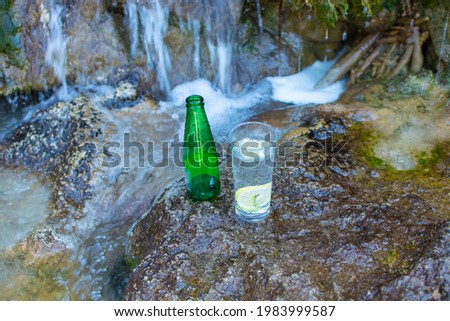 a glass of mineral water and a bottle with it.