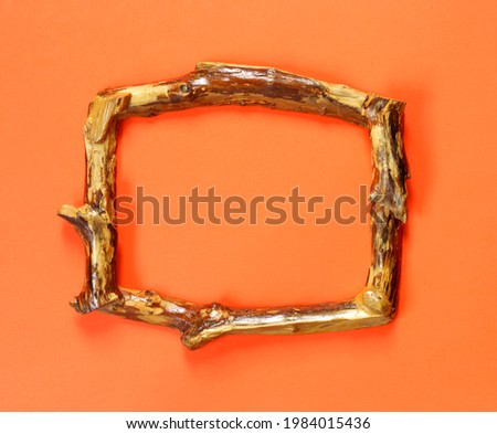 Wooden brown frame on  orange wall in retro style. Interior concept. Modern home decor. 
Banner background.