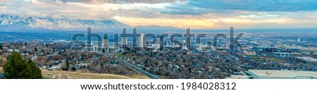 Entire view of buildings and residential houses of Salt Lake City in Utah. There are facilities and residential buildings with roads and large buildings in the middle with mountain view at the back.