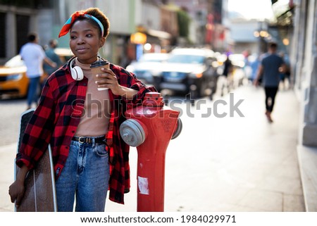 Portrait of happy african-american woman with skateboard. Young stylish woman with skateboard outdoors.