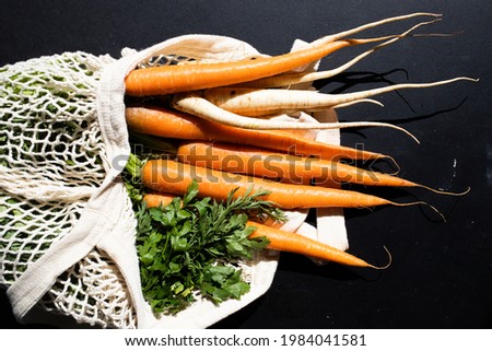 bunch of fresh carrots and parsley in an eco bag. Zero waste, plastic free concept. Sustainable lifestyle. Reusable cotton and mesh eco bags for shopping
