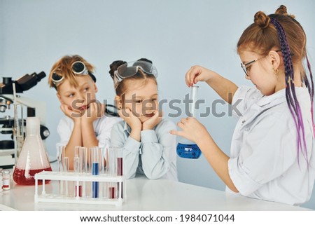 Children in white coats plays a scientists in lab by using equipment.