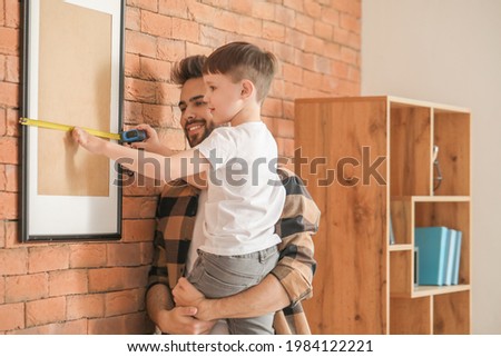 Father and son with taking measures of frame at home