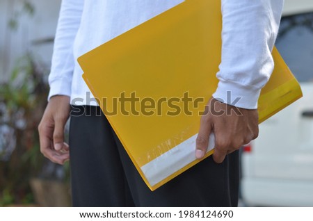 male hands bring yellow document in outdoor view